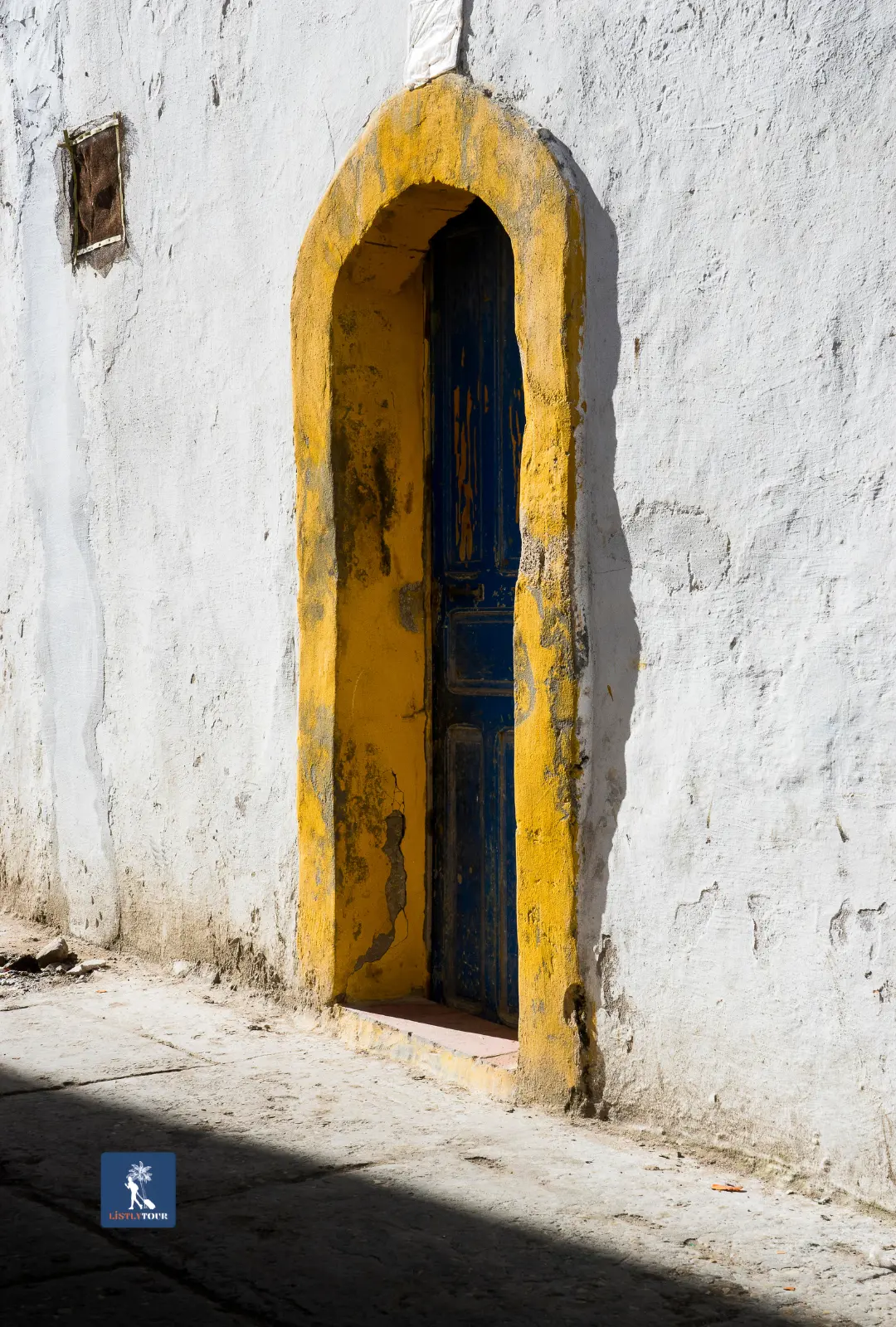 Blue wooden door framed in yellow, photographed during the Ida Ougourd market tour from Essaouira